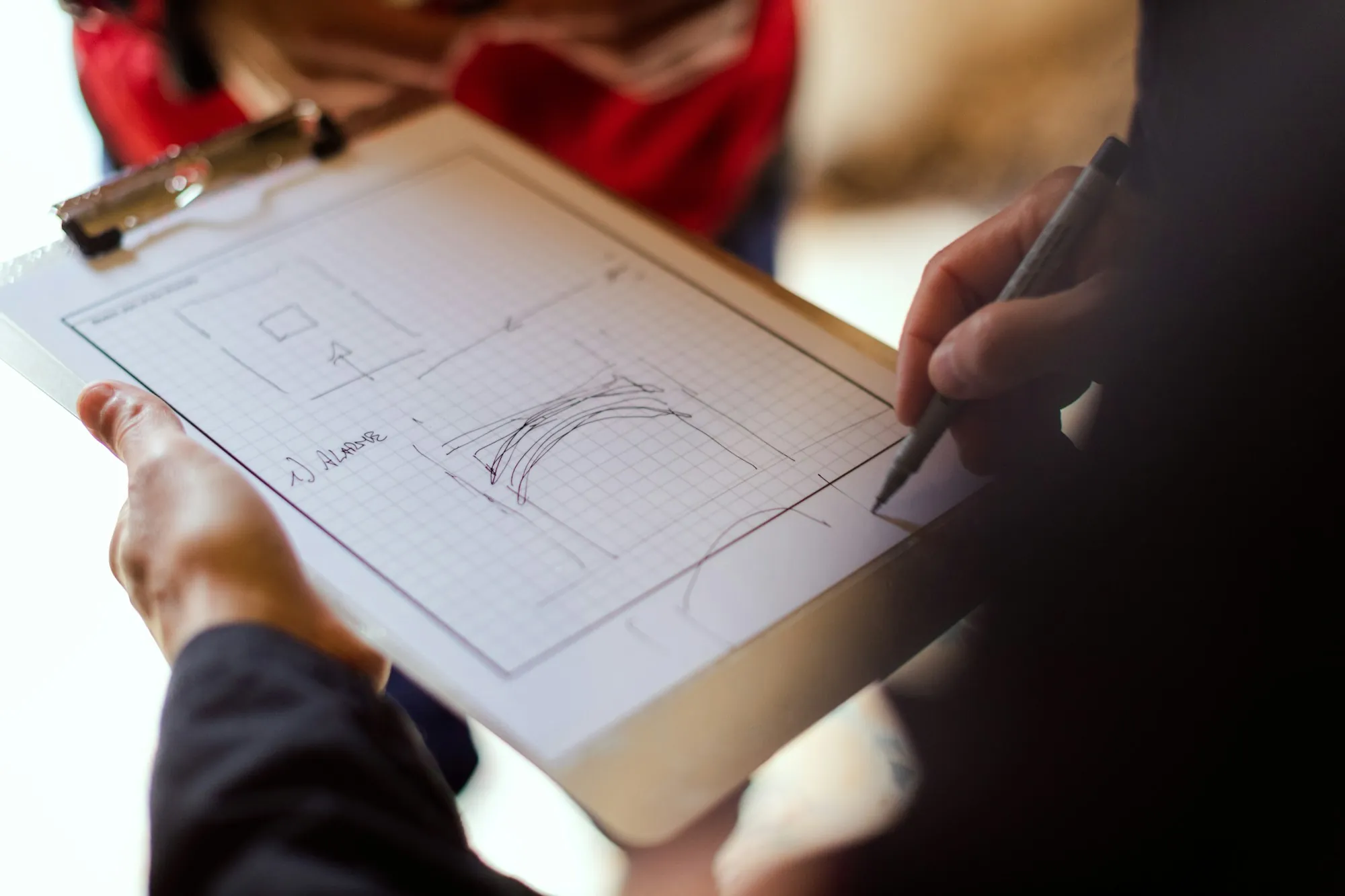 Hand sketching a floor plan on a clipboard