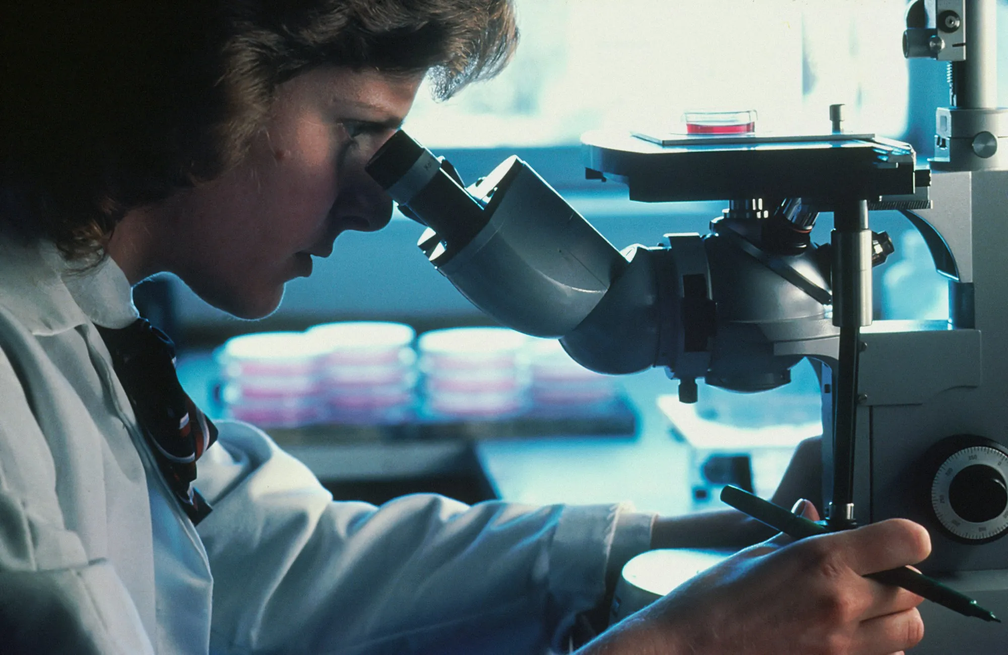 Analyst examining a sample through a microscope